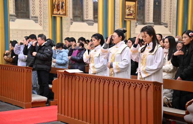 Members of the Catholic clergy and devotees attend the Christmas Eve mass at the Xishiku Church in Beijing on December 24, 2025. (Photo by Adek BERRY / AFP)