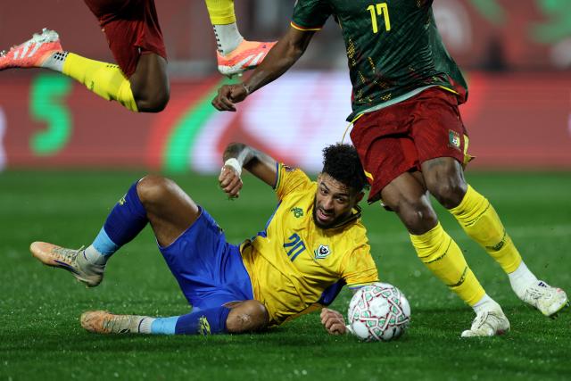 Gabon's forward #20 Denis Bouanga is tackled by Cameroon's defender #17 Samuel Kotto during the Africa Cup of Nations (CAN) Group F football match between Cameroon and Gabon at Adrar Stadium in Agadir on December 24, 2025. (Photo by FRANCK FIFE / AFP)