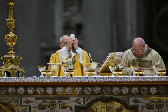 Pope Leo XIV carries out communion as he performs the Christmas Eve mass at St Peter's Basilica in the Vatican on December 24, 2025. (Photo by Andreas SOLARO / AFP)