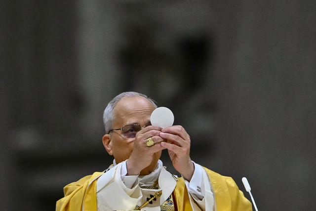 Pope Leo XIV carries out communion as he performs the Christmas Eve mass at St Peter's Basilica in the Vatican on December 24, 2025. (Photo by Andreas SOLARO / AFP)