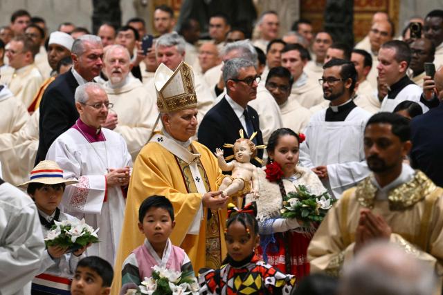 Pope Leo XIV carries the statue of the Baby Jesus at the end of the Christmas Eve mass at St Peter's Basilica in the Vatican on December 24, 2025. (Photo by Andreas SOLARO / AFP)