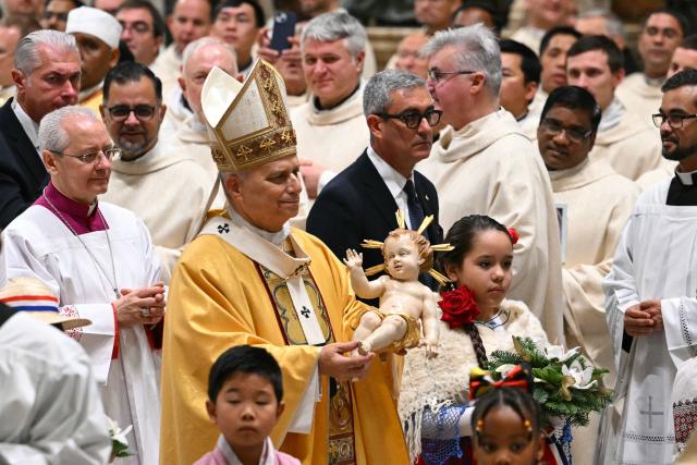 Pope Leo XIV carries the statue of the Baby Jesus at the end of the Christmas Eve mass at St Peter's Basilica in the Vatican on December 24, 2025. (Photo by Andreas SOLARO / AFP)