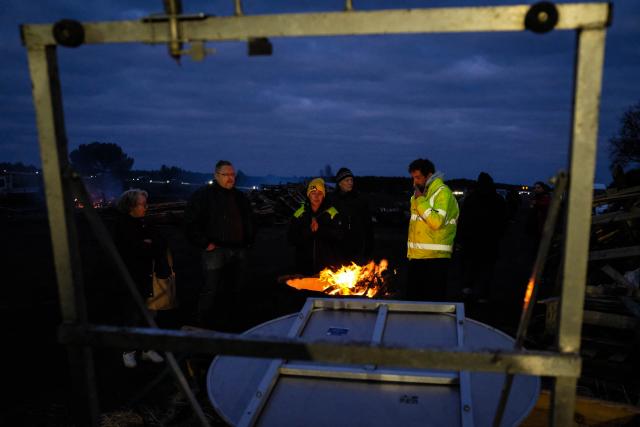 CORRECTION / Protesters stand beside a fire during a road blockade on the A63 motorway amid a farmers's protest against the government's mandatory culling protocol for cattle herds affected by lumpy skin disease (dermatose nodulaire contagieuse), in Cestas, near Bordeaux, south-western France, on December 24, 2025. (Photo by Thomas BERNARDI / AFP) / The erroneous mention[s] appearing in the metadata of this photo by Matthieu RONDEL has been modified in AFP systems in the following manner: [Thomas BERNARDI] instead of [Mathieu RONDEL]. Please immediately remove the erroneous mention from all your online services and delete it from your servers. If you have been authorized by AFP to distribute it to third parties, please ensure that the same actions are carried out by them. Failure to promptly comply with these instructions will entail liability on your part for any continued or post notification usage. Therefore we thank you very much for all your attention and prompt action. We are sorry for the inconvenience this notification may cause and remain at your disposal for any further information you may require.