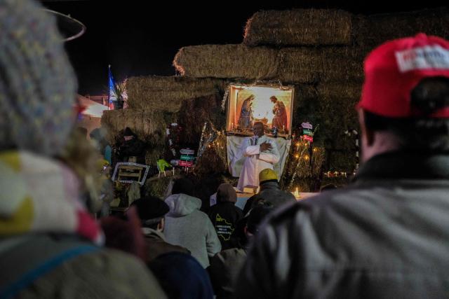 Protesters attend a Christmas eve mass during a road blockade on the A63 motorway amid a farmers's protest against the government's mandatory culling protocol for cattle herds affected by lumpy skin disease (dermatose nodulaire contagieuse), in Cestas, near Bordeaux, south-western France, on December 24, 2025. (Photo by Thomas BERNARDI / AFP)