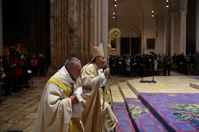 French bishop of Chartres Monsignor Philippe Christory (R) and French rector of the cathedral Emmanuel Blondeau (L) present a statue representing Baby Jesus after celebrating midnight Christmas mass at Cathedral of Our Lady of Chartres in Chartres, north-central France, southwest of Paris, on December 25, 2025. (Photo by JEAN-FRANCOIS MONIER / AFP)