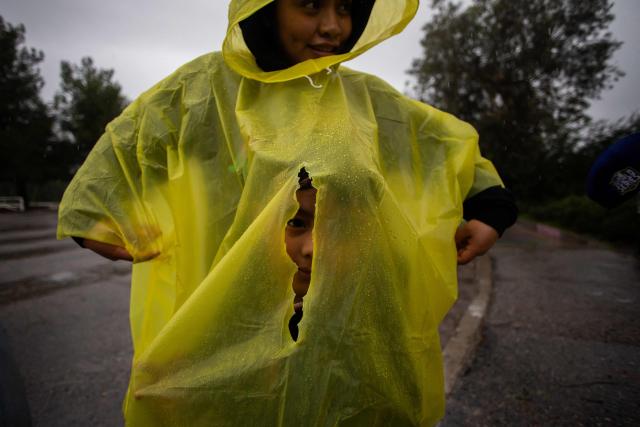 A boy looks through a hole at his mother's rain poncho while they walk at Elysian Park in the rain on December 24, 2025 in Los Angeles, California. A major winter storm rolled into California on December 23, forcing hundreds of evacuations in burn areas while threatening flooding and travel delays through Christmas for much of the state, officials said.
A "strong atmospheric river brings heavy rain, snow, and wind to California through Friday," the National Weather Service said in a statement on December 23, warning anyone in northern, central and southern parts of the state to "exercise extreme caution." (Photo by Apu GOMES / AFP)