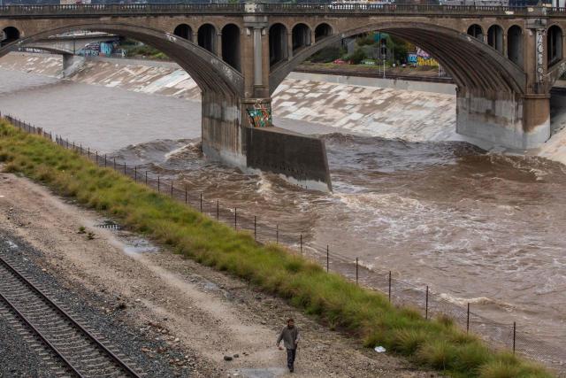 A man walks along the Los Angeles river during heavy rainfall on December 24, 2025 in Los Angeles, California. A major winter storm rolled into California on December 23, forcing hundreds of evacuations in burn areas while threatening flooding and travel delays through Christmas for much of the state, officials said.
A "strong atmospheric river brings heavy rain, snow, and wind to California through Friday," the National Weather Service said in a statement on December 23, warning anyone in northern, central and southern parts of the state to "exercise extreme caution." (Photo by Apu GOMES / AFP)
