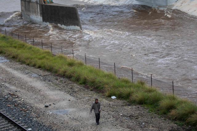 A man walks along the Los Angeles river during heavy rainfall on December 24, 2025 in Los Angeles, California. A major winter storm rolled into California on December 23, forcing hundreds of evacuations in burn areas while threatening flooding and travel delays through Christmas for much of the state, officials said.
A "strong atmospheric river brings heavy rain, snow, and wind to California through Friday," the National Weather Service said in a statement on December 23, warning anyone in northern, central and southern parts of the state to "exercise extreme caution." (Photo by Apu GOMES / AFP)