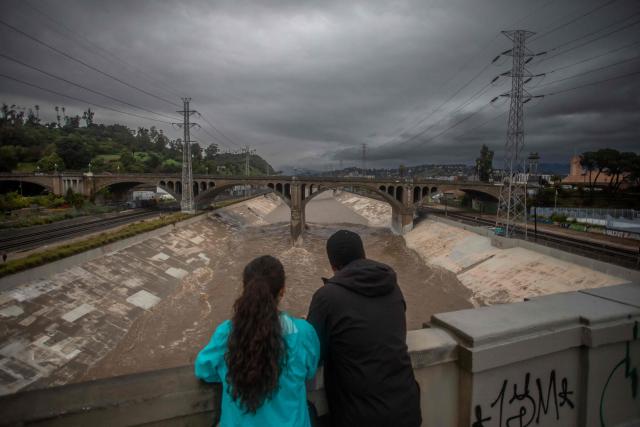 A couple watches the high water level of the Los Angeles river after heavy rains on December 24, 2025 in Los Angeles, California. A major winter storm rolled into California on December 23, forcing hundreds of evacuations in burn areas while threatening flooding and travel delays through Christmas for much of the state, officials said.
A "strong atmospheric river brings heavy rain, snow, and wind to California through Friday," the National Weather Service said in a statement on December 23, warning anyone in northern, central and southern parts of the state to "exercise extreme caution." (Photo by Apu GOMES / AFP)