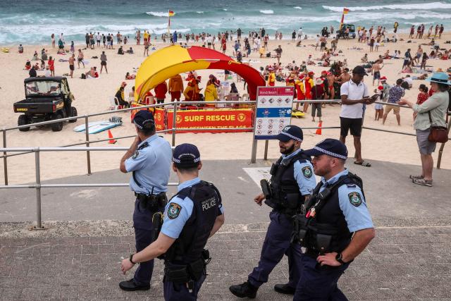 Police officers patrol near beachgoers on Christmas Day at Bondi Beach in Sydney on December 25, 2025. (Photo by DAVID GRAY / AFP)