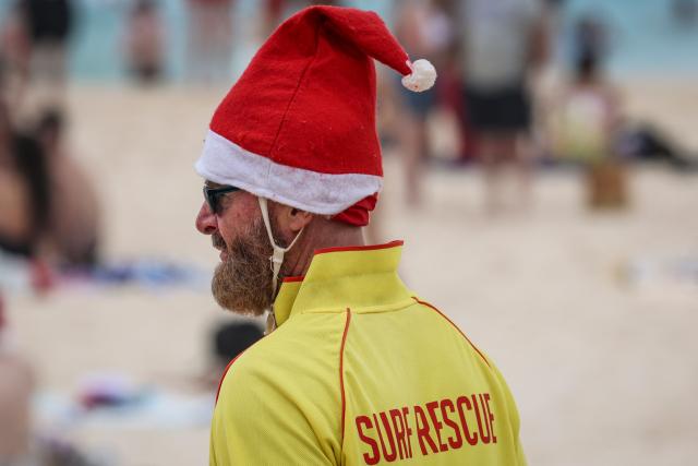 A surf lifesaver wearing a Christmas hat patrols at Bondi Beach in Sydney on December 25, 2025. (Photo by DAVID GRAY / AFP)