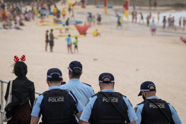 Police officers patrol near beachgoers on Christmas Day at Bondi Beach in Sydney on December 25, 2025. (Photo by DAVID GRAY / AFP)