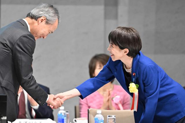 Japan's Prime Minister Sanae Takaichi (R) is greeted by Yoshinobu Tsutsui, Chairman of the Japan Business Federation, or Keidanren, upon her arrival at the 14th Keidanren Council Meeting in Tokyo on December 25, 2025. (Photo by Kazuhiro NOGI / AFP)