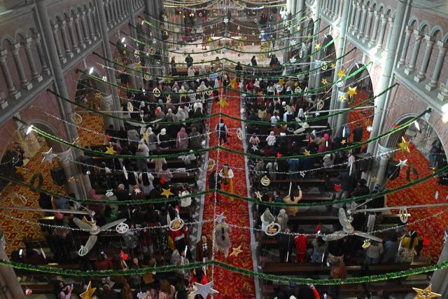 Christians pray during Christmas mass at Sacred Heart Cathedral in Lahore on December 25, 2025. (Photo by Arif ALI / AFP)