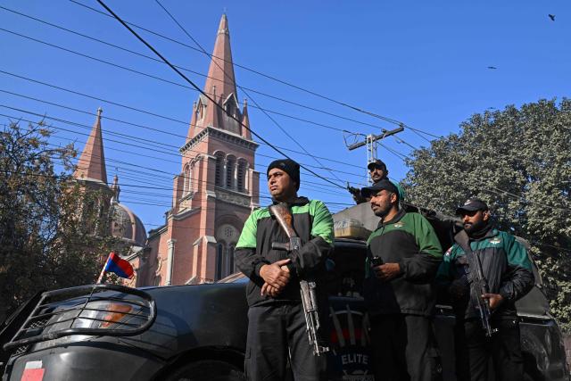 Policemen stand guard during Christmas mass at Sacred Heart Cathedral in Lahore on December 25, 2025. (Photo by Arif ALI / AFP)