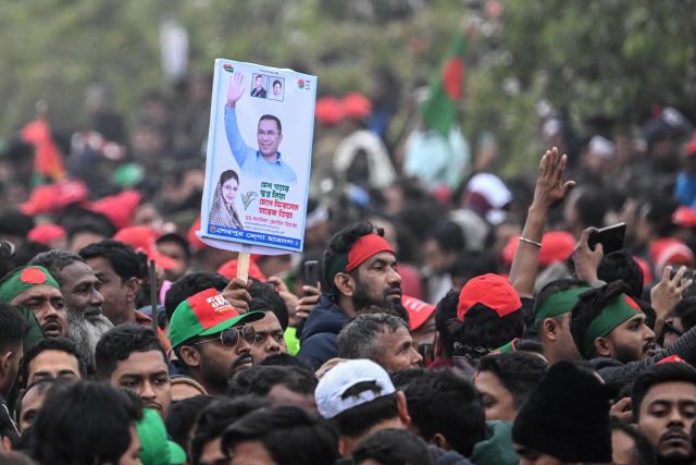 A supporter of Tarique Rahman, son of former prime minister Khaleda Zia and Bangladesh Nationalist Party (BNP)'s apparent heir holds a poster with their portraits during a rally after Rahman's arrival in Dhaka on December 25, 2025. Aspiring prime minister and political heavyweight Rahman was welcomed back to Bangladesh on December 25 by huge crowds of joyous supporters after 17 years in self-imposed exile. (Photo by Munir UZ ZAMAN / AFP)