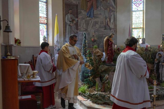 Abouna Bashar Basiel leads a Christmas morning mass at the Christ the Redeemer Church in the mostly Christian town of Taybeh, in the Israeli-occupied West Bank on December 25, 2025. (Photo by ILIA YEFIMOVICH / AFP)