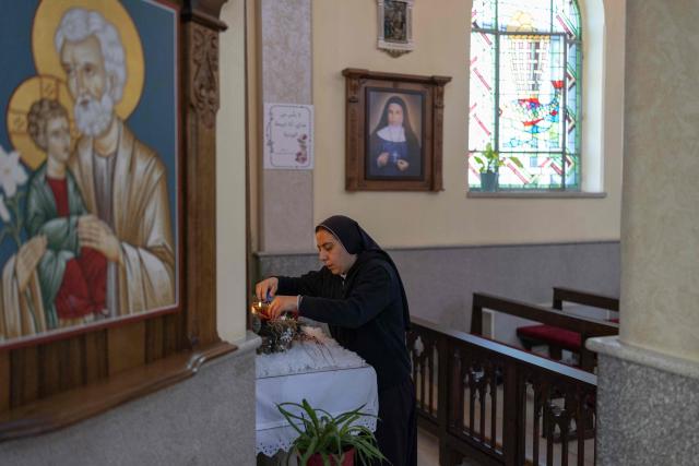 A nun lights a candle during a Christmas morning mass at the Christ the Redeemer Church in the mostly Christian town of Taybeh, in the Israeli-occupied West Bank on December 25, 2025. (Photo by ILIA YEFIMOVICH / AFP)