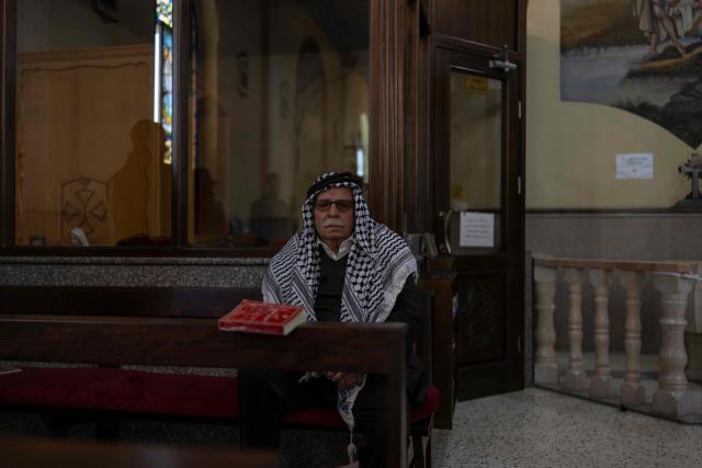 A worshipper attends a Christmas morning mass wearing a keffiyeh at the Christ the Redeemer Church in the mostly Christian town of Taybeh, in the Israeli-occupied West Bank on December 25, 2025. (Photo by ILIA YEFIMOVICH / AFP)