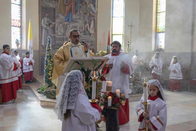 Abouna Bashar Basiel leads a Christmas morning mass at the Christ the Redeemer Church in the mostly Christian town of Taybeh, in the Israeli-occupied West Bank on December 25, 2025. (Photo by ILIA YEFIMOVICH / AFP)