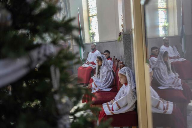 Altar servers react during a Christmas morning mass at the Christ the Redeemer Church in the mostly Christian town of Taybeh, in the Israeli-occupied West Bank on December 25, 2025. (Photo by ILIA YEFIMOVICH / AFP)