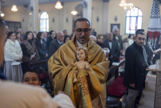 Abouna Bashar Basiel leads a Christmas morning mass at the Christ the Redeemer Church in the mostly Christian town of Taybeh, in the Israeli-occupied West Bank on December 25, 2025. (Photo by ILIA YEFIMOVICH / AFP)