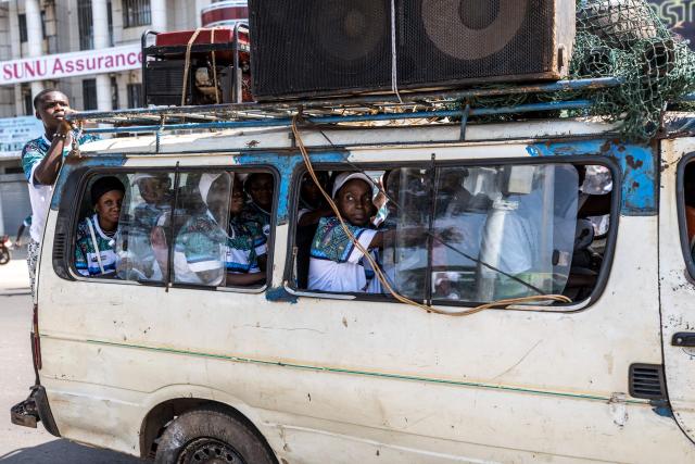 A supporter of Guinea President and presidential candidate Mamady Doumbouya looks outside of a vehicle during the last day of campaign in Conakry, on December 25, 2025, ahead of Guinea’s Presidential election on December 28, 2025. (Photo by PATRICK MEINHARDT / AFP)