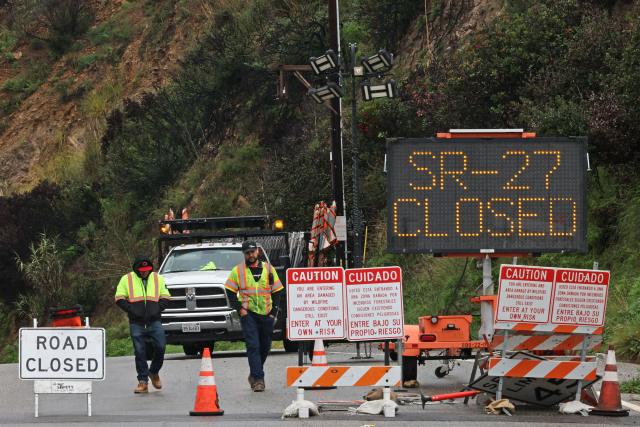 CORRECTION / Work crews are seen at a road closure on State Route 27 and Pacific Coast Highway due to the heavy storms impacting Southern California on December 25, 2025 in Topanga, California. Torrential rains unleashed flash floods and warnings of debris flow across southern California, particularly in fire-scarred areas, with further downpours forecast for Thursday as authorities declared a state of emergency in several counties. Driven by an atmospheric river known as "the Pineapple Express," which moves heavy moisture from the tropical climes of Hawaii to the US West Coast, the storm was expected to deliver months' worth of rain over a few days. (Photo by Jonathan ALCORN / AFP) / The erroneous mention[s] appearing in the metadata of this photo by Robyn Beck has been modified in AFP systems in the following manner: [Jonathan Alcorn] instead of [Robyn Beck]. Please immediately remove the erroneous mention[s] from all your online services and delete it (them) from your servers. If you have been authorized by AFP to distribute it (them) to third parties, please ensure that the same actions are carried out by them. Failure to promptly comply with these instructions will entail liability on your part for any continued or post notification usage. Therefore we thank you very much for all your attention and prompt action. We are sorry for the inconvenience this notification may cause and remain at your disposal for any further information you may require.