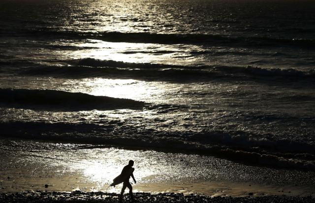A surfer walks by the sea at Taghzout beach on December 25, 2025. (Photo by FRANCK FIFE / AFP)
