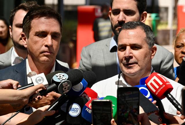 The chief physician of the team caring for former Brazil's President (2019–2023) Jair Bolsonaro, Claudio Birolini (R), speaks with the press next to cardiologist Brasil Ramos Caiado, after Bolsonaro underwent inguinal hernia surgery at DF Star Hospital, in Brasнlia, on December 25, 2025. Bolsonaro, who is serving a 27-year prison sentence for an attempted coup, underwent a "successful" surgery his wife announced in an Instagram post. (Photo by Evaristo Sa / AFP)