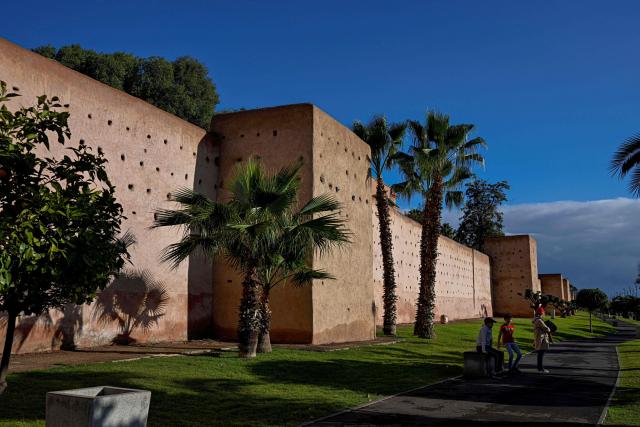 Tourists rsit in the shade next to the historical wall in the old district of Marrakech on December 25, 2025, during the Africa Cup of Nations (CAN) football tournament. (Photo by Khaled DESOUKI / AFP)