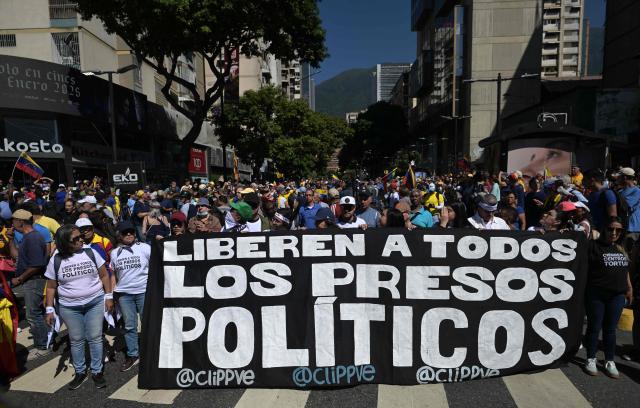 (FILES) Demonstrators hold a banner demanding for the release of all political prisoners during a protest called by the opposition on the eve of the presidential inauguration, in Caracas on January 9, 2025. At least 60 post-election detainees were released from prison on December 25, 2025, a non-governmental organisation made up of human rights activists and relatives of political prisoners reported. Those released had been arrested amid the political crisis triggered by President Nicolas Maduro's re-election in July 2024 for a third term amid allegations of fraud from the opposition. (Photo by JUAN BARRETO / AFP)