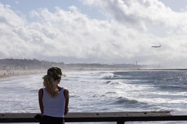 A person looks out over the Pacific Ocean from the Venice Pier during a break in the rain storms affecting Southern California on December 25, 2025 in Venice, California. Torrential rains unleashed flash floods and warnings of debris flow across southern California, particularly in fire-scarred areas, with further downpours forecast for Thursday as authorities declared a state of emergency in several counties. Driven by an atmospheric river known as "the Pineapple Express," which moves heavy moisture from the tropical climes of Hawaii to the US West Coast, the storm was expected to deliver months' worth of rain over a few days. (Photo by Jonathan Alcorn / AFP)