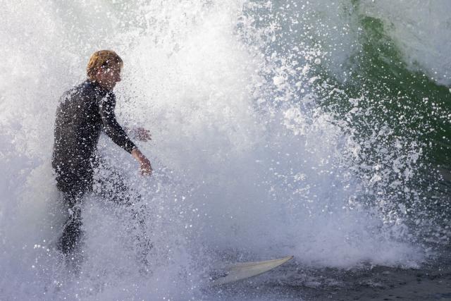 A surfer rides a wave near the Venice Pier during a break in the rain storms affecting Southern California on December 25, 2025 in Venice, California. Torrential rains unleashed flash floods and warnings of debris flow across southern California, particularly in fire-scarred areas, with further downpours forecast for Thursday as authorities declared a state of emergency in several counties. Driven by an atmospheric river known as "the Pineapple Express," which moves heavy moisture from the tropical climes of Hawaii to the US West Coast, the storm was expected to deliver months' worth of rain over a few days. (Photo by Jonathan Alcorn / AFP)