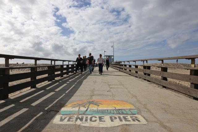 People visit the Venice Pier during a break in the rain storms affecting Southern California on December 25, 2025 in Venice, California. Torrential rains unleashed flash floods and warnings of debris flow across southern California, particularly in fire-scarred areas, with further downpours forecast for Thursday as authorities declared a state of emergency in several counties. Driven by an atmospheric river known as "the Pineapple Express," which moves heavy moisture from the tropical climes of Hawaii to the US West Coast, the storm was expected to deliver months' worth of rain over a few days. (Photo by Jonathan Alcorn / AFP)