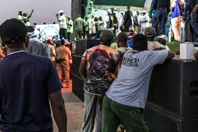 A private security officer wears a t-shirt bearing the image of Guinean President and presidential candidate Mamady Doumbouya during his final campaign rally in Conakry on December 25, 2025. Guinean voters head to the polls for a presidential election on December 28, 2025. (Photo by PATRICK MEINHARDT / AFP)