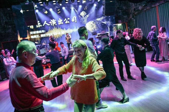 This photo taken on December 10, 2025 shows elderly guests dancing at the Shiguang Dance Hall in the Putuo district of Shanghai. It was just a regular Wednesday at a lunchtime dance club in Shanghai, where dance hall culture has been deeply rooted in the city's identity since its jazz-age heyday. On any given day, multiple venues host hours-long daytime sessions across the finance hub, some starting as early as 6 am. Establishments like the historic Paramount Ballroom are time capsules from the 1930s, while others flash with neon pink and green rave lights in the early afternoon. (Photo by Hector RETAMAL / AFP) / To go with 'CHINA-LIFESTYLE-DANCE-HISTORY-DEMOGRAPHICS, REPORTAGE' by Rita QIAN