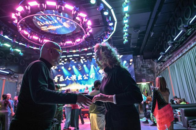 This photo taken on December 10, 2025 shows Zhou Yaqin (R) dancing with a partner at the Shiguang Dance Hall in the Putuo district of Shanghai. It was just a regular Wednesday at a lunchtime dance club in Shanghai, where dance hall culture has been deeply rooted in the city's identity since its jazz-age heyday. On any given day, multiple venues host hours-long daytime sessions across the finance hub, some starting as early as 6 am. Establishments like the historic Paramount Ballroom are time capsules from the 1930s, while others flash with neon pink and green rave lights in the early afternoon. (Photo by Hector RETAMAL / AFP) / To go with 'CHINA-LIFESTYLE-DANCE-HISTORY-DEMOGRAPHICS, REPORTAGE' by Rita QIAN