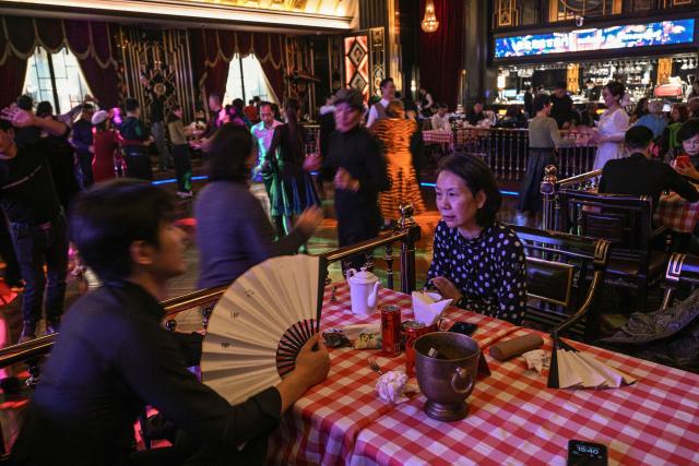 This photo taken on December 11, 2025 shows elderly guests waiting to dance at the Hai Shang Jiu Meng Dance Hall in the Changning district of Shanghai. It was just a regular Wednesday at a lunchtime dance club in Shanghai, where dance hall culture has been deeply rooted in the city's identity since its jazz-age heyday. On any given day, multiple venues host hours-long daytime sessions across the finance hub, some starting as early as 6 am. Establishments like the historic Paramount Ballroom are time capsules from the 1930s, while others flash with neon pink and green rave lights in the early afternoon. (Photo by Hector RETAMAL / AFP) / To go with 'CHINA-LIFESTYLE-DANCE-HISTORY-DEMOGRAPHICS, REPORTAGE' by Rita QIAN