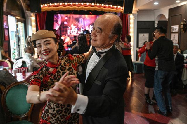 TOPSHOT - This photo taken on December 10, 2025 shows Wang Li, 65, dancing with a partner at the Hai Shang Jiu Meng Dance Hall in the Changning district of Shanghai. It was just a regular Wednesday at a lunchtime dance club in Shanghai, where dance hall culture has been deeply rooted in the city's identity since its jazz-age heyday. On any given day, multiple venues host hours-long daytime sessions across the finance hub, some starting as early as 6 am. Establishments like the historic Paramount Ballroom are time capsules from the 1930s, while others flash with neon pink and green rave lights in the early afternoon. (Photo by Hector RETAMAL / AFP) / To go with 'CHINA-LIFESTYLE-DANCE-HISTORY-DEMOGRAPHICS, REPORTAGE' by Rita QIAN