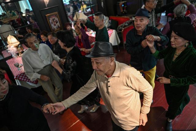 This photo taken on December 10, 2025 shows elderly guests dancing at the Hai Shang Jiu Meng Dance Hall in the Changning district of Shanghai. It was just a regular Wednesday at a lunchtime dance club in Shanghai, where dance hall culture has been deeply rooted in the city's identity since its jazz-age heyday. On any given day, multiple venues host hours-long daytime sessions across the finance hub, some starting as early as 6 am. Establishments like the historic Paramount Ballroom are time capsules from the 1930s, while others flash with neon pink and green rave lights in the early afternoon. (Photo by Hector RETAMAL / AFP) / To go with 'CHINA-LIFESTYLE-DANCE-HISTORY-DEMOGRAPHICS, REPORTAGE' by Rita QIAN