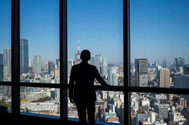 This photo taken on November 28, 2025 shows a man looking out the window at the view from a high-rise building in Tokyo. The Japanese government approved on December 26, a record budget for the upcoming fiscal year, media reported, to pay for everything from bigger defence spending to ballooning social security costs as persistent inflation continues to bite. (Photo by Kazuhiro NOGI / JIJI Press / AFP) / Japan OUT