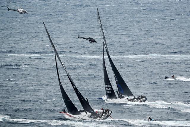 Yacht LawConnect (R) competes against Master Lock Comanche out of Sydney Heads during the annual Sydney to Hobart yacht race on Boxing Day at Sydney Harbour on December 26, 2025. (Photo by Saeed Khan / AFP)