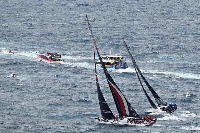 SHK Scallywag 100 (L) and URM Group competes out of Sydney Heads during the annual Sydney to Hobart yacht race on Boxing Day at Sydney Harbour on December 26, 2025. (Photo by Saeed Khan / AFP)