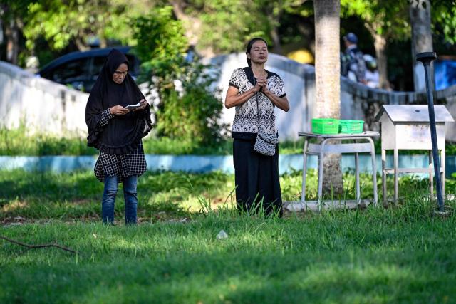 People pray for relatives who lost their lives in the 2004 Indian Ocean tsunami at a mass grave in Siron, Aceh province on December 26, 2025. On December 26, 2004, a magnitude 9.1 earthquake struck the coast of Sumatra in Indonesia and triggered a huge tsunami across the Indian Ocean that killed more than 220,000 people in a dozen countries. (Photo by CHAIDEER MAHYUDDIN / AFP)