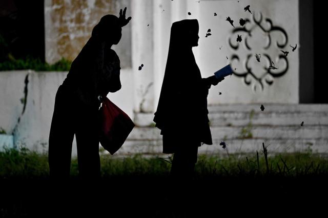 People pray for relatives who lost their lives in the 2004 Indian Ocean tsunami at a mass grave in Siron, Aceh province on December 26, 2025. On December 26, 2004, a magnitude 9.1 earthquake struck the coast of Sumatra in Indonesia and triggered a huge tsunami across the Indian Ocean that killed more than 220,000 people in a dozen countries. (Photo by CHAIDEER MAHYUDDIN / AFP)