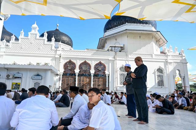People gather to pray for relatives who lost their lives in the 2004 Indian Ocean tsunami at a mass grave at the grand mosque Baiturrahman in Banda Aceh on December 26, 2025. (Photo by CHAIDEER MAHYUDDIN / AFP)