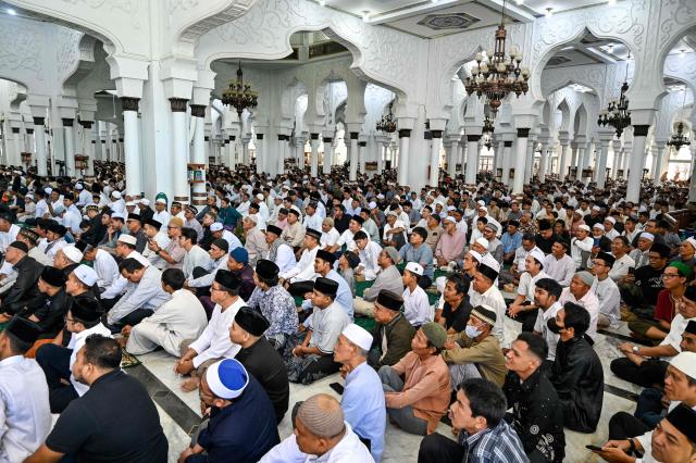 People gather to pray for relatives who lost their lives in the 2004 Indian Ocean tsunami at a mass grave at the grand mosque Baiturrahman in Banda Aceh on December 26, 2025.2025. (Photo by CHAIDEER MAHYUDDIN / AFP)