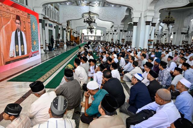 People gather to pray for relatives who lost their lives in the 2004 Indian Ocean tsunami at a mass grave at the grand mosque Baiturrahman in Banda Aceh on December 26, 2025. (Photo by CHAIDEER MAHYUDDIN / AFP)