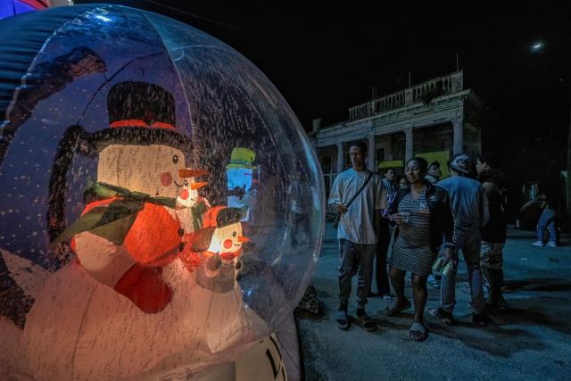 Residents gather around a house powered by a generator and decorated with Santa Claus inflatables to celebrate Christmas amid a blackout in Havana on December 25, 2025. (Photo by Adalberto ROQUE / AFP)